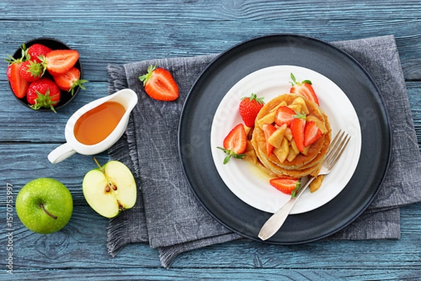 Fototapeta pancakes topped with apple slices and strawberries