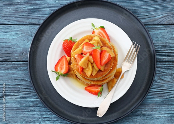 Fototapeta pancakes topped with apple slices and strawberries