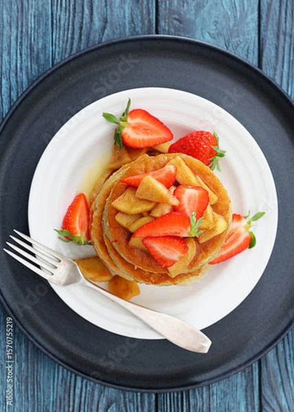 Fototapeta pancakes topped with apple slices and strawberries