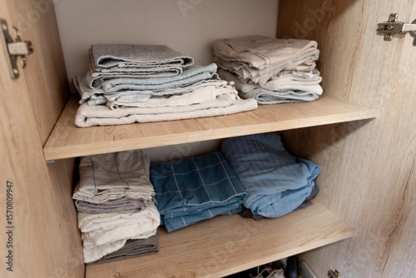Fototapeta Bed linen, sheets and pillowcases and towels neatly stacked in closet in bedroom