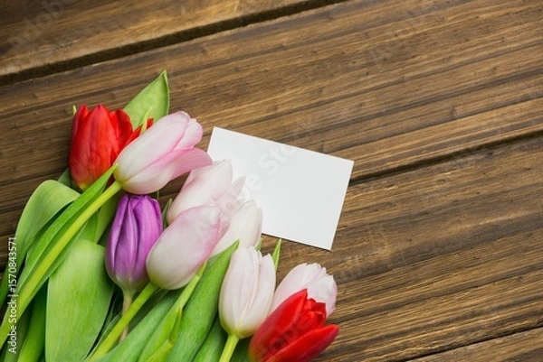 Obraz Multicolored tulip bouquet is being shown in flat design on plank tabletop with blank white card