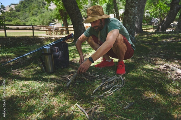 Fototapeta Man Preparing Kindling for a Campfire in a Forest on a Summer Day