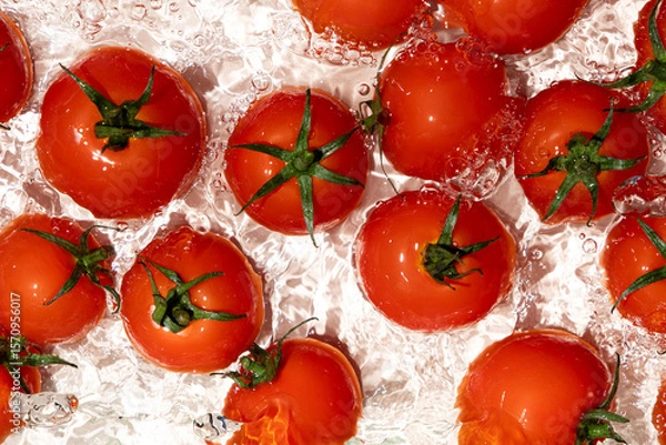 Fototapeta Vegetable background of fresh whole tomatoes in water, splash of water, top view.