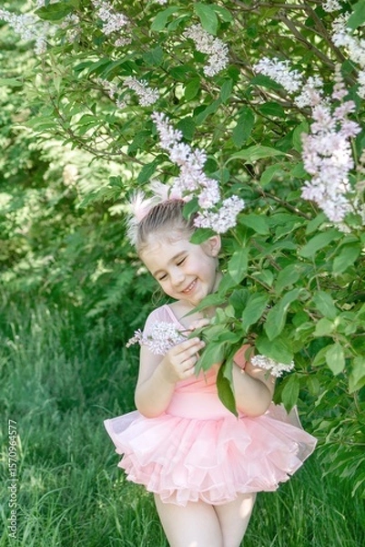 Fototapeta Portrait of Enchanting Little Girl in Pink Tutu Enjoying Lilac Blossoms in Serene Garden Setting.