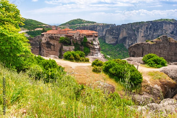 Fototapeta Medieval Greek monastery built on rocky cliff surrounded by mountains in Meteora Greece