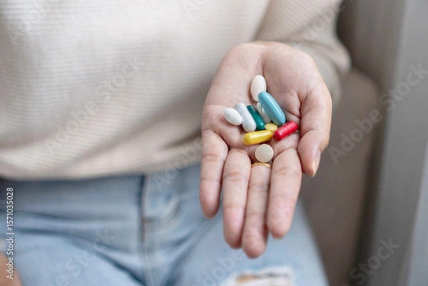 Fototapeta Close-up of a woman’s hand holding various pills, capsules, and vitamins, showing daily health care, supplement use, or the risk of taking too much medicine