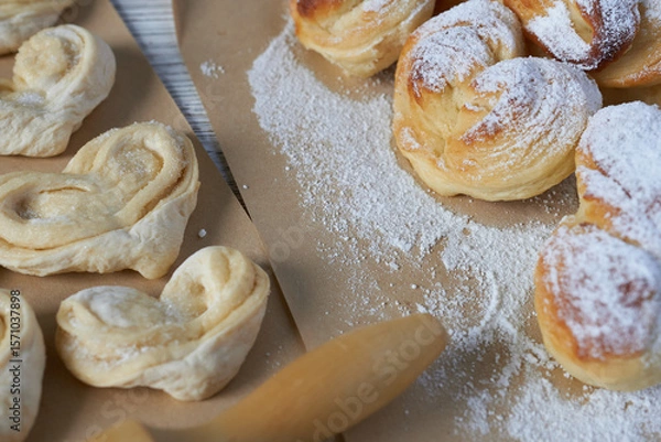 Fototapeta Close-up of homemade puff pastry with powdered sugar on wooden table. Vanilla buns.