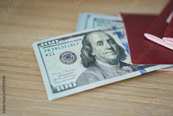 Fototapeta Dollars in red passport on wooden background. Selective focus.