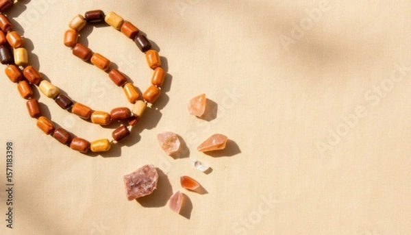 Fototapeta Colorful beaded necklace and assorted natural stones arranged on a light background in bright sunlight