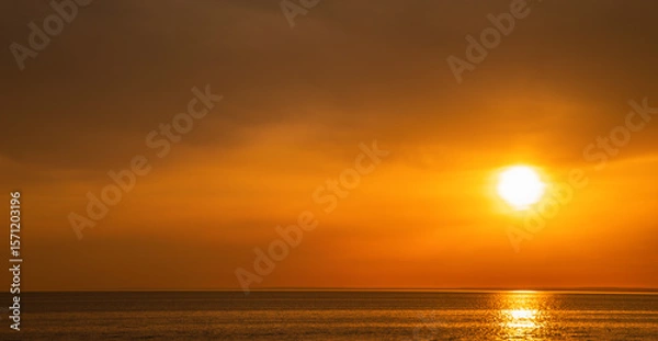 Obraz Beautiful sunset over the sea. The sun is setting on the water. The sky is painted with bright colors. Summer evening at sunset beach. Horizontal banner background with copy space.