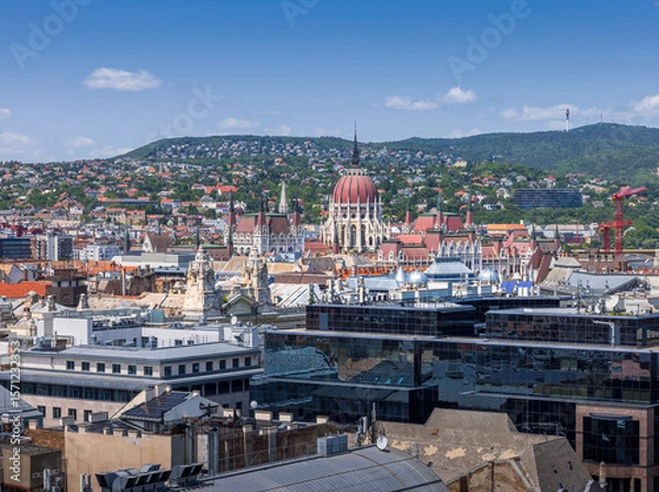 Fototapeta Panoramic view of Budapest with the iconic Hungarian Parliament and Buda Hills, captured from the observation deck of St. Stephen’s Basilica on a clear summer day.