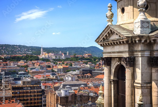 Fototapeta Panoramic view of Matthias Church and Fisherman's Bastion in Budapest, with Buda Hills in the background, captured from the dome of St. Stephen’s Basilica on a sunny summer day.