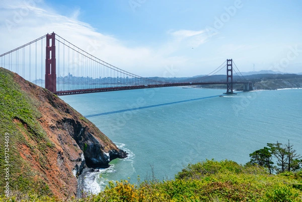 Fototapeta Iconic view of the Golden Gate Bridge stretching across the blue waters of the San Francisco Bay, seen from a green cliffside near Kirby Cove. A timeless symbol of California travel and nature
