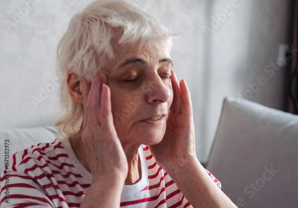 Obraz Old Age, Health Problem, Vision and People Concept - Close Up of Senior Woman Sitting on Sofa and Having Headache at Home. Elderly Woman With A Migraine