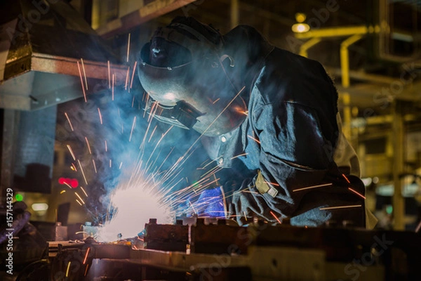 Obraz Industrial worker is welding metal in factory
