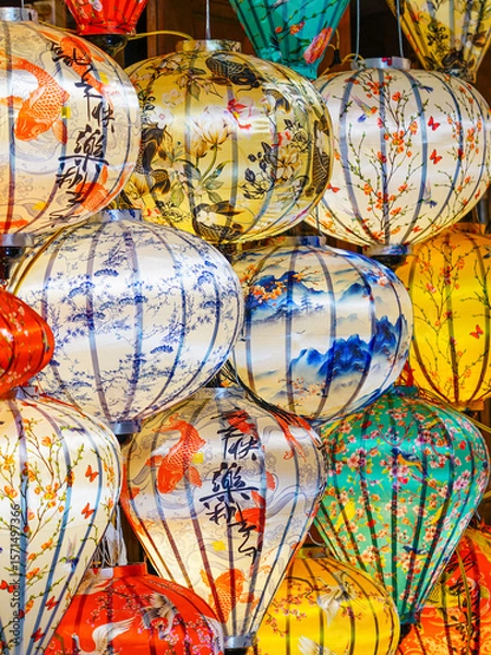 Fototapeta Close-up of vibrant Vietnamese silk lanterns with koi, blossoms, and calligraphy designs on display