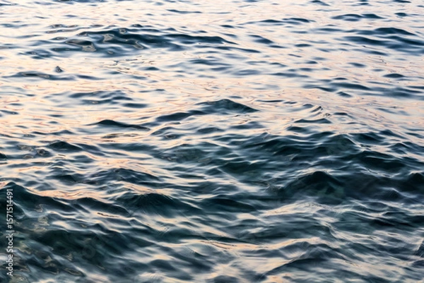 Fototapeta close up of calm sea water surface under sunset light. water texture. sunlight reflection. abstract liquid background