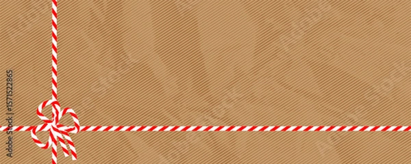 Fototapeta A festive background with a kraft paper texture and a red and white candy cane ribbon. Perfect for Christmas gifts, holiday packaging and winter designs