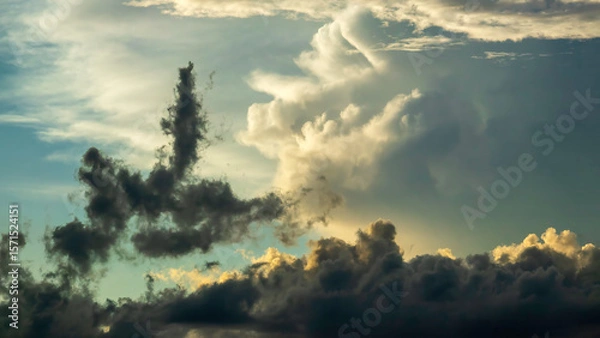 Obraz Cloudscape with one anomalous cloud in prominent silhouette, as if upended by an updraft, during golden hour on a humid evening early in summer, southwest Florida. Motifs of local unpredictability.