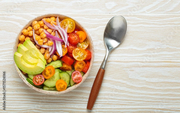 Fototapeta Healthy chickpea salad with ripe avocado, juicy cherry tomatoes, crisp cucumber, and red onion slices. Perfect for a nutritious and healthy meal