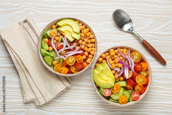 Fototapeta Two bowls of healthy chickpea salad with ripe avocado, juicy cherry tomatoes, crisp cucumber, and red onion slices. Perfect for a nutritious and healthy meal
