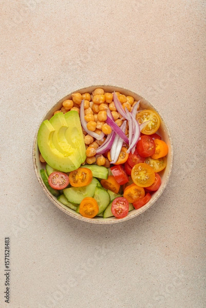 Obraz Healthy chickpea salad with ripe avocado, juicy cherry tomatoes, crisp cucumber, and red onion slices. Perfect for a nutritious and healthy meal, light beige background