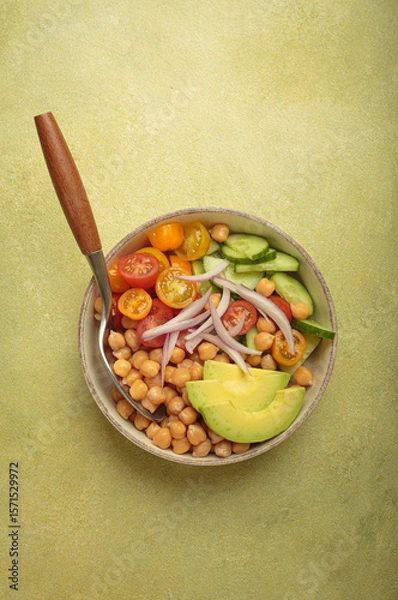 Obraz Healthy chickpea salad with ripe avocado, juicy cherry tomatoes, crisp cucumber, and red onion slices. Perfect for a nutritious and healthy meal on light green background