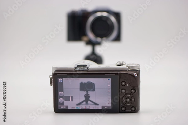 Fototapeta Camera setup on a tripod with a digital display showing reflection of another camera behind it