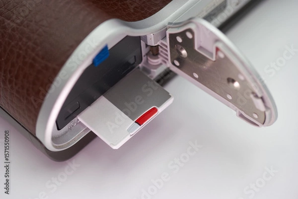 Fototapeta Close up view of a camera revealing the memory card compartment with a silver and red memory card inserted