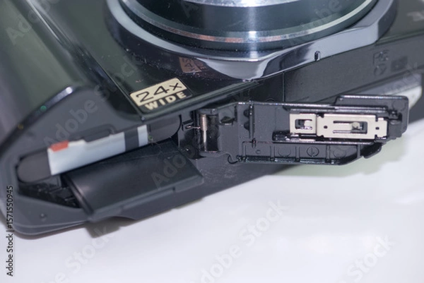 Fototapeta Camera showcasing a 24x wide zoom lens with an open compartment for battery and memory card access