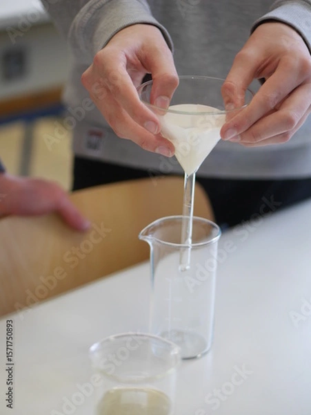 Obraz Person is pouring a liquid into a glass beaker
