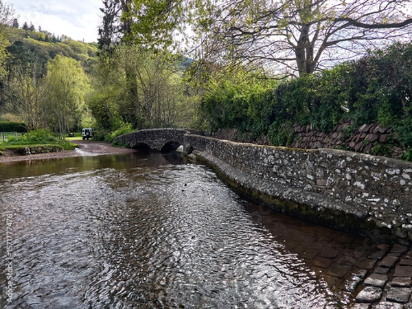 Fototapeta Dunster UK, March 15, 2025. The Gallox Bridge in Dunster, Somerset, England dates from the 15th century. with two arches over the River Avill. It was originally known as Gallows Bridge