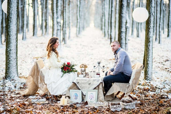 Fototapeta Winter wedding newlyweds sitting at a decorated table in rustic style