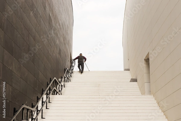 Obraz Old man climbing up the stairs with his walking stick