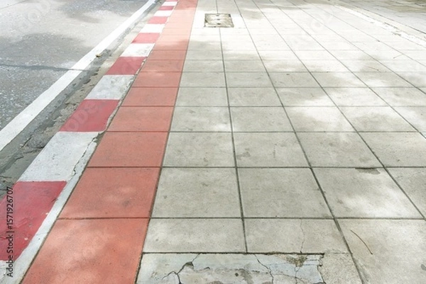 Fototapeta Concrete paver sidewalk, red white curb and road perspective view texture background