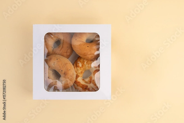 Fototapeta Bagels in a white box on a beige background, top view