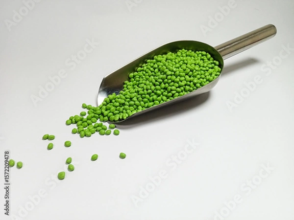 Fototapeta Green plastic masterbatch, polymer carries colorful pigments with small scoops poured into a white background, suitable for product catalog design of industrial plastic manufacturing company profiles