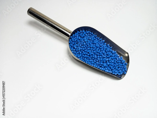 Fototapeta Blue plastic masterbatch, polymer carries colorful pigments with small scoops poured into a white background, suitable for product catalog design of industrial plastic manufacturing company profiles