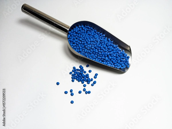 Fototapeta Blue plastic masterbatch, polymer carries colorful pigments with small scoops poured into a white background, suitable for product catalog design of industrial plastic manufacturing company profiles