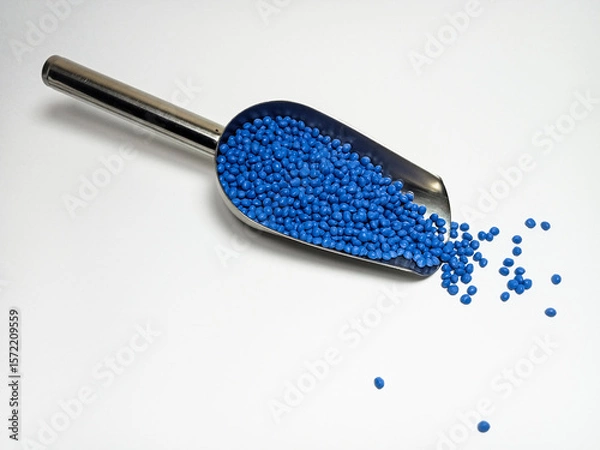 Fototapeta Blue plastic masterbatch, polymer carries colorful pigments with small scoops poured into a white background, suitable for product catalog design of industrial plastic manufacturing company profiles