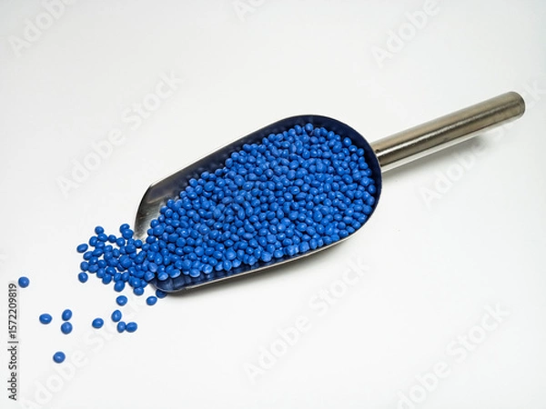 Fototapeta Blue plastic masterbatch, polymer carries colorful pigments with small scoops poured into a white background, suitable for product catalog design of industrial plastic manufacturing company profiles