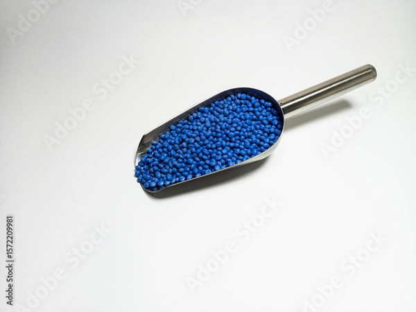 Fototapeta Blue plastic masterbatch, polymer carries colorful pigments with small scoops poured into a white background, suitable for product catalog design of industrial plastic manufacturing company profiles