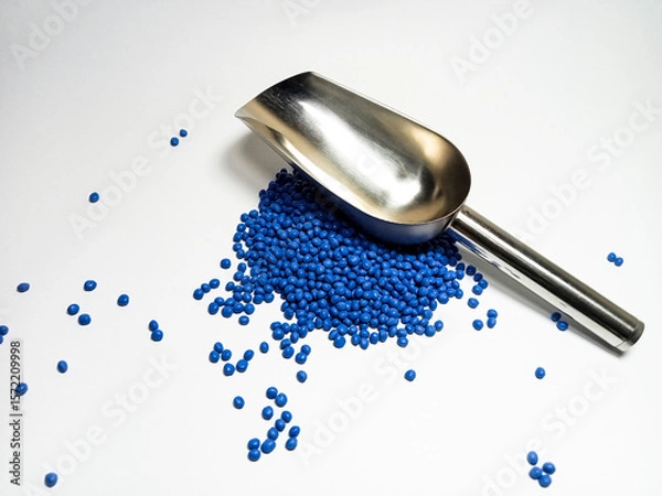 Fototapeta Blue plastic masterbatch, polymer carries colorful pigments with small scoops poured into a white background, suitable for product catalog design of industrial plastic manufacturing company profiles