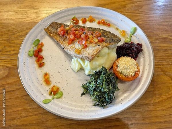 Fototapeta Grilled seabass steak served with spinach, berry jam, vegetables and mashed potatoes