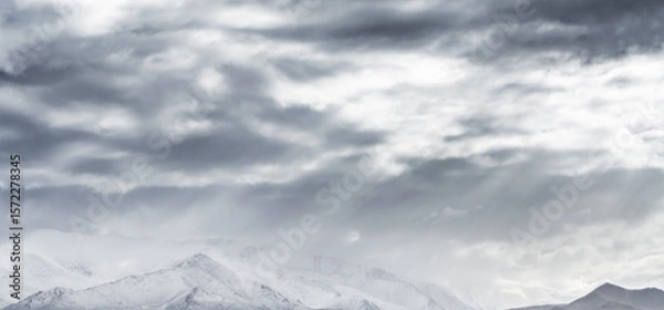 Fototapeta Dramatic landscape panorama of mountain peaks with snow and glaciers in cloudy weather, rays of the sun breaking through the clouds, landscape of the Pamir mountains for the background