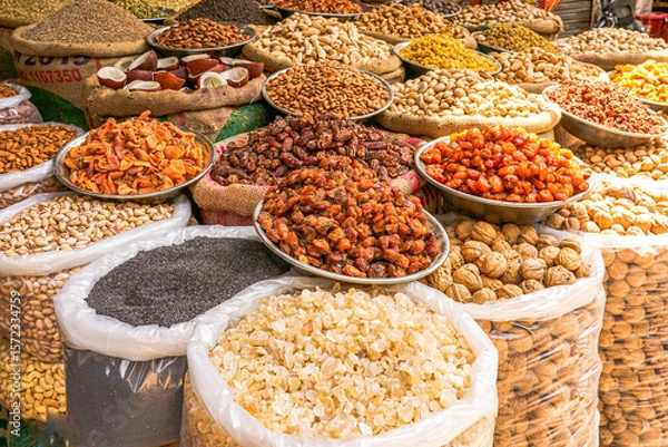 Fototapeta A colorful market display of spices, nuts, and dried fruits in bowls and sacks, showcasing culinary richness, cultural heritage, and natural food diversity.