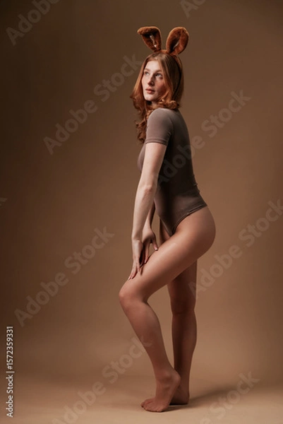 Fototapeta Freckled redhead posing with bunny ears and confident look in bodysuit