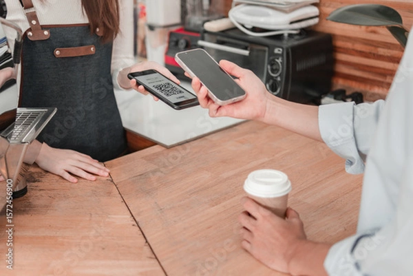 Obraz Customer making mobile payment for coffee in cozy urban  atmosphere with engaging experience