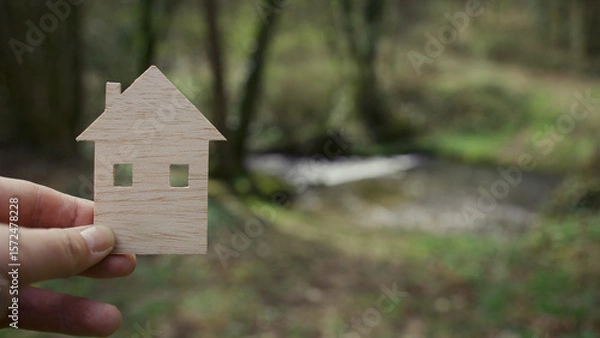 Obraz A man's hand holds a wooden model of a house.