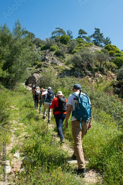 Fototapeta People trekking in Latmos mountains in spring. Latmos Caria trekking route. Latmos trekking route among historical ruins. Hiking from Latmos Mountain to Lake Bafa. Walking by Lake Bafa.